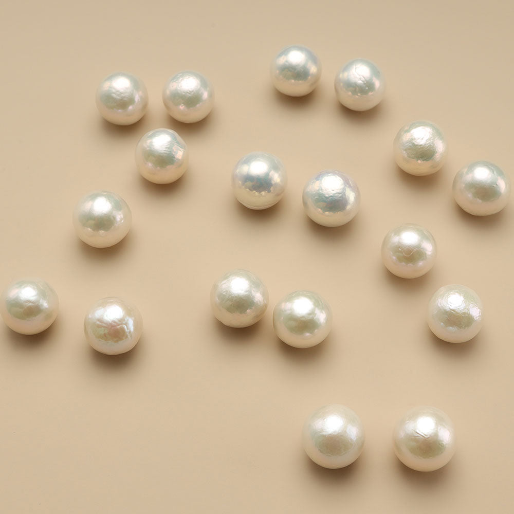 Eighteen 12mm pearl beads on brown cloth.
