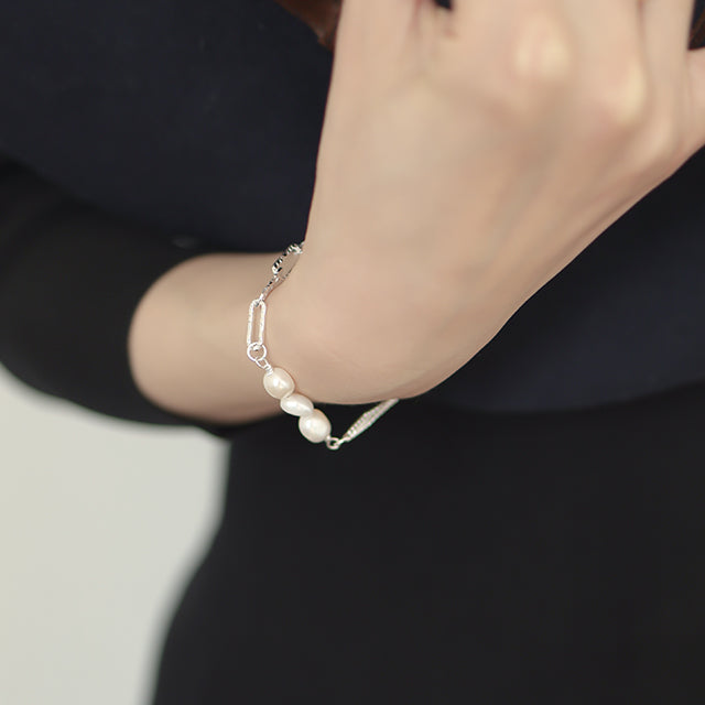 A woman dress in black wear silver pearl bracelet.