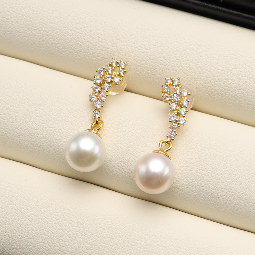 A pair of shining pearl drop earrings.