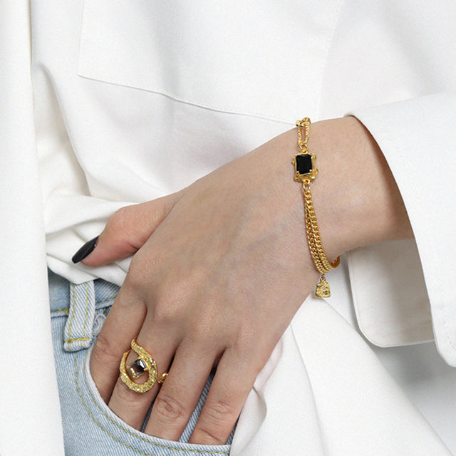 A women dress in white wear gold charm bracelets.