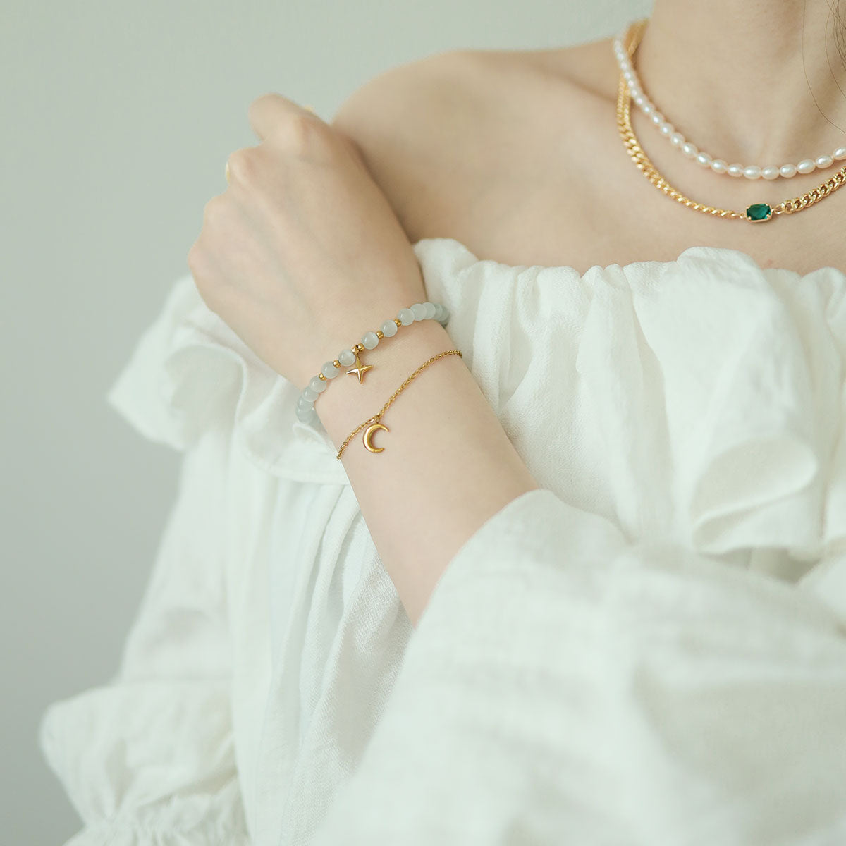 Women wear birthstone charm bracelet and emerald chain necklace.