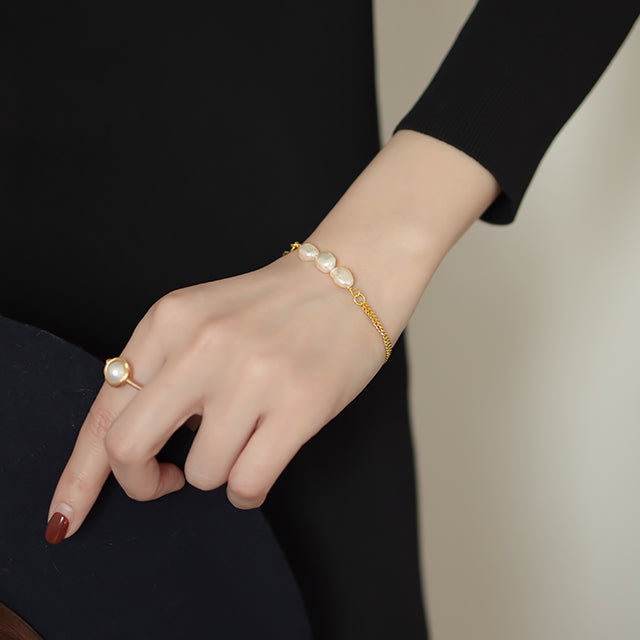 A woman dress in black wear pearl bracelet and pearl ring.