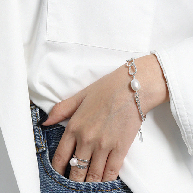 A women dress in white wear silver pearl bracelet and pearl ring.