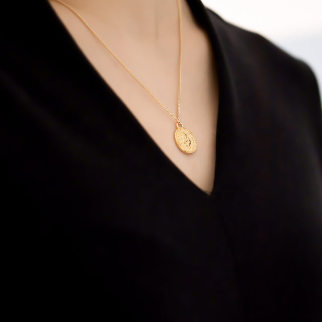 Women in black wear coin pendant.