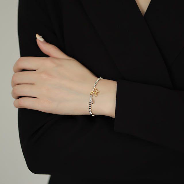 Women in black wear a gold and silver bracelet.
