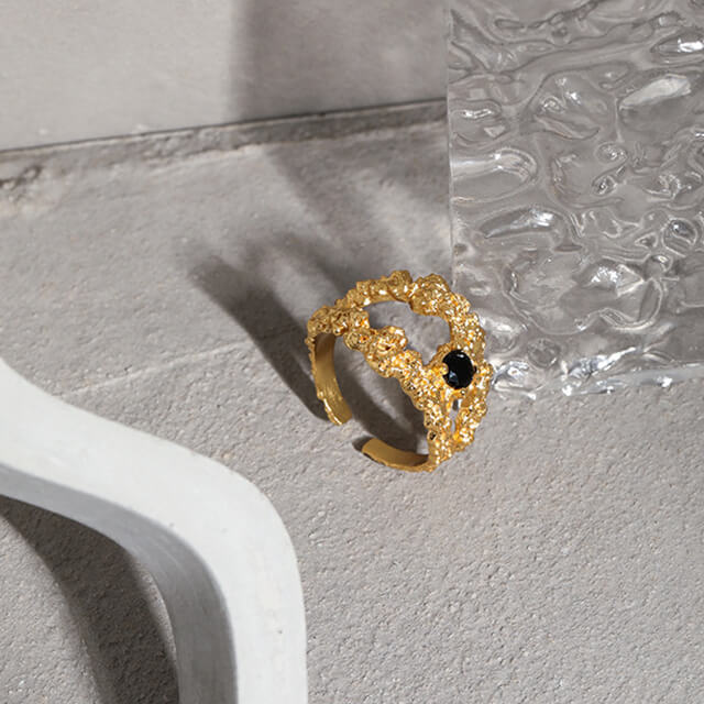 Gold black stone ring next to the glass.