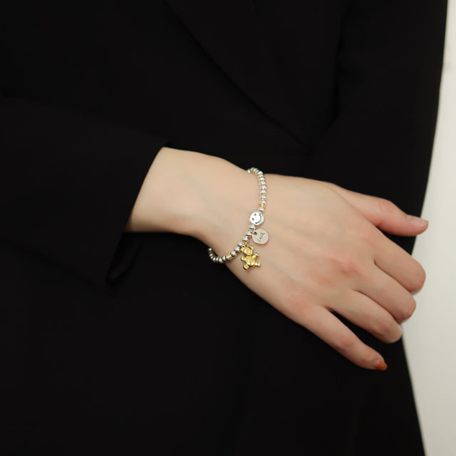 Women in black wear a gold charm bracelet.