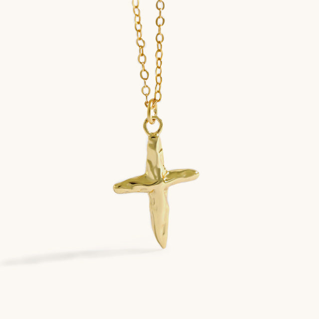 A dangling gold cross necklace.