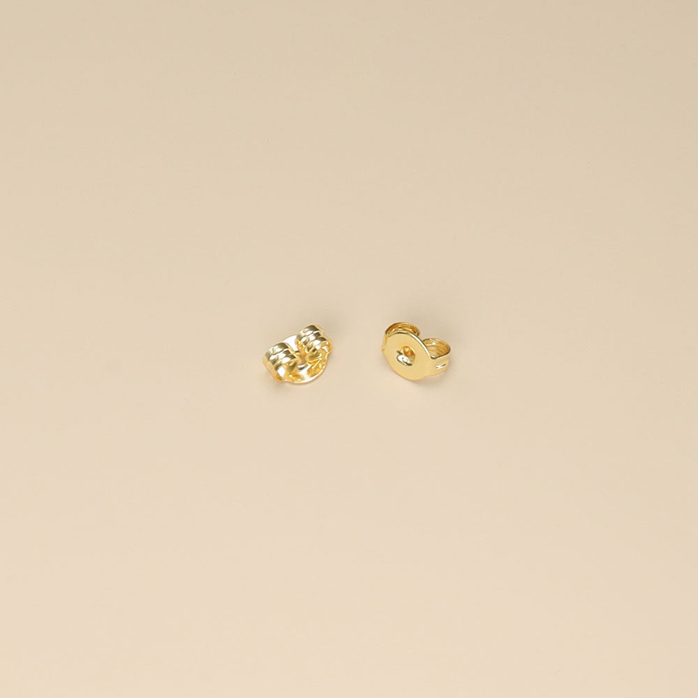 A pair of gold earrings backs.