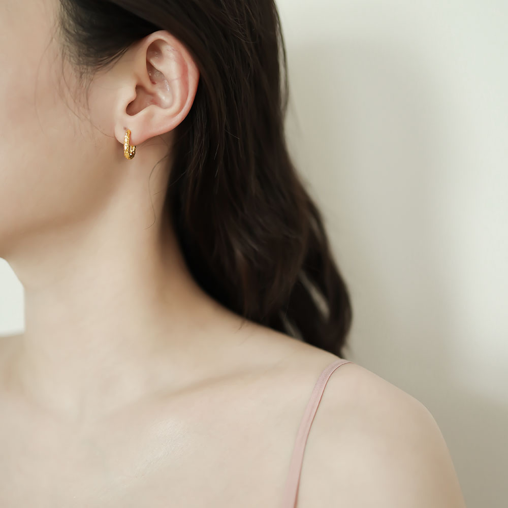 Women wear a gold huggie hoop earring.