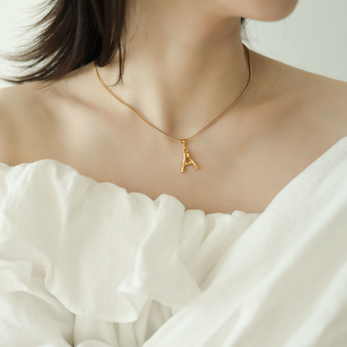 Women wear gold initial necklace with A.