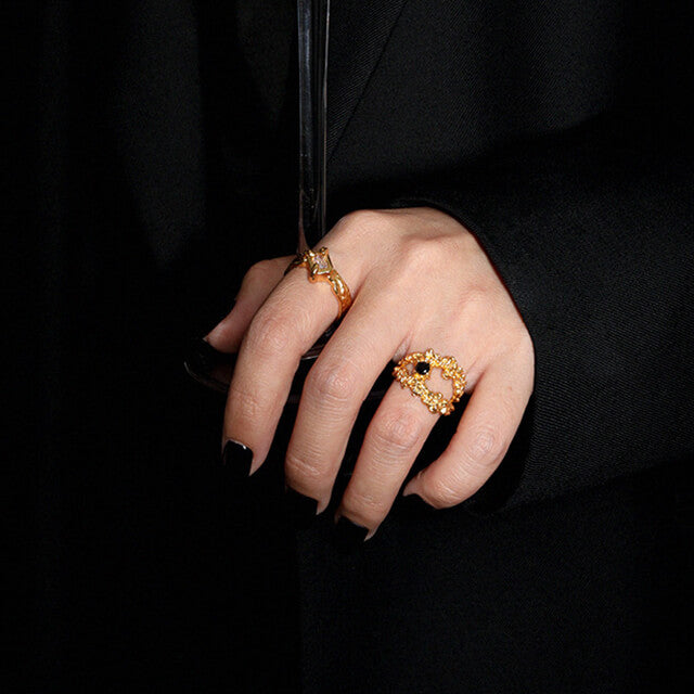 A women in black wear two gold ladies rings.