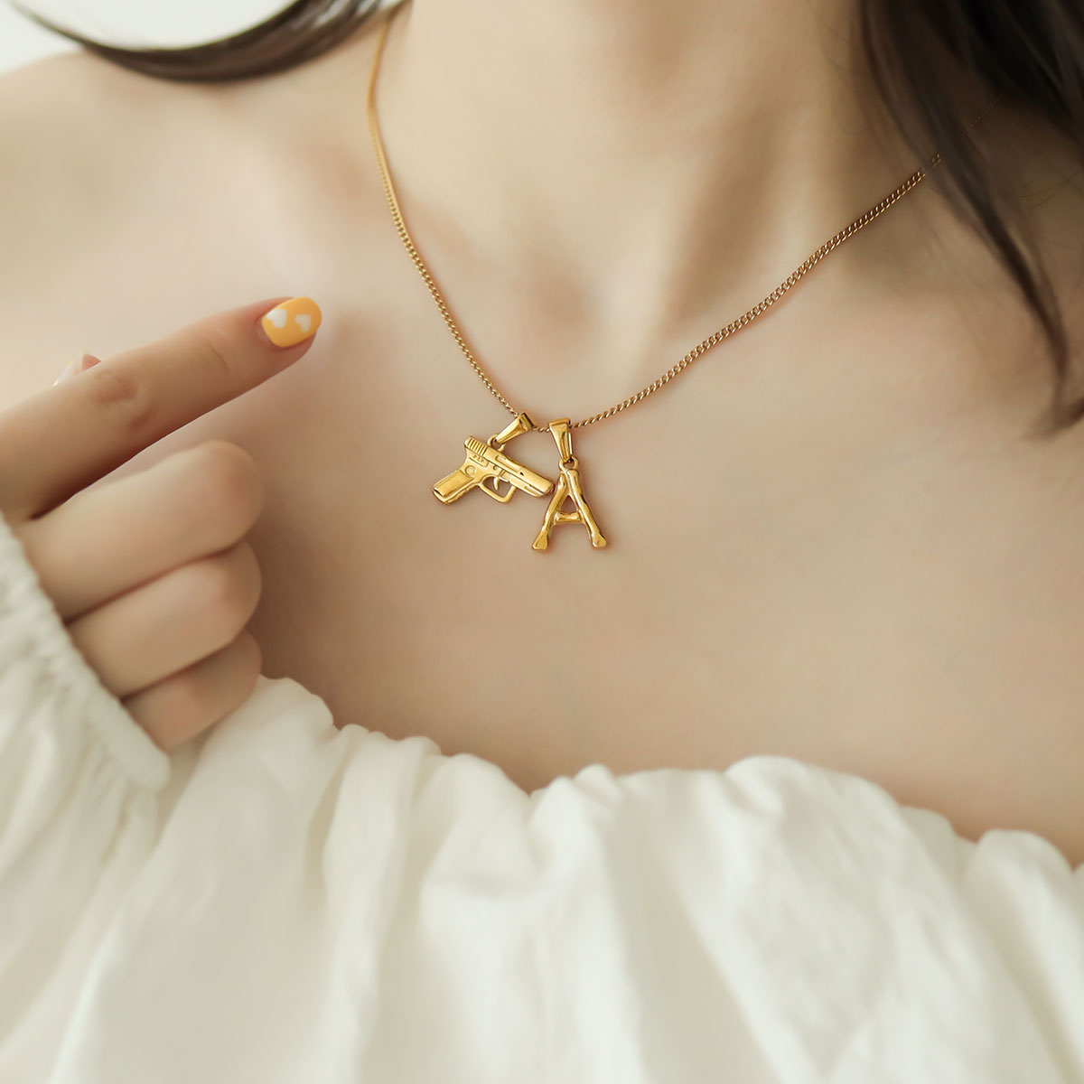 Women wear gold letter necklace with A and gun.