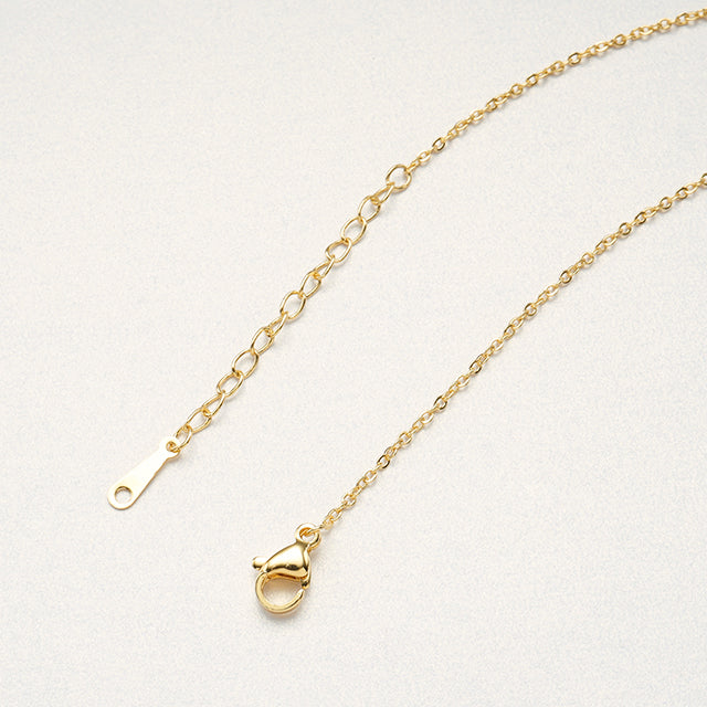 Adjustable gold necklace clasp on cream paper.