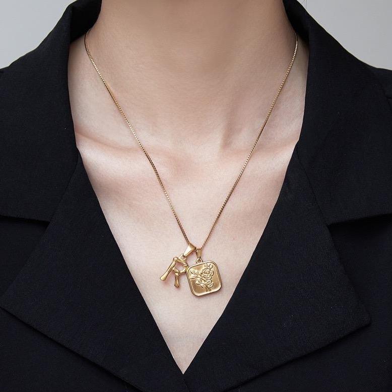 Women wear gold necklace with initial charm.