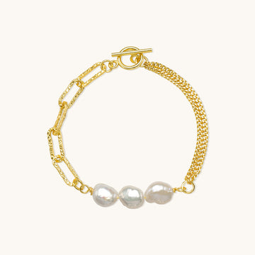 A gold pearl hand chain bracelet.