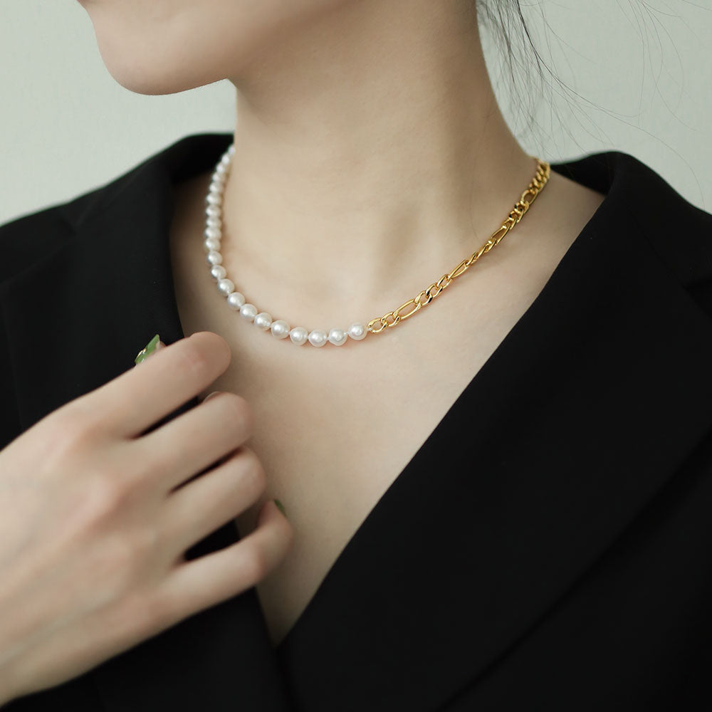 Women in black wear gold pearl necklace.