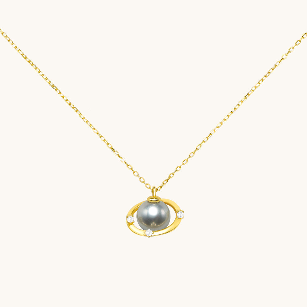 A gold saturn necklace with gray pearl.