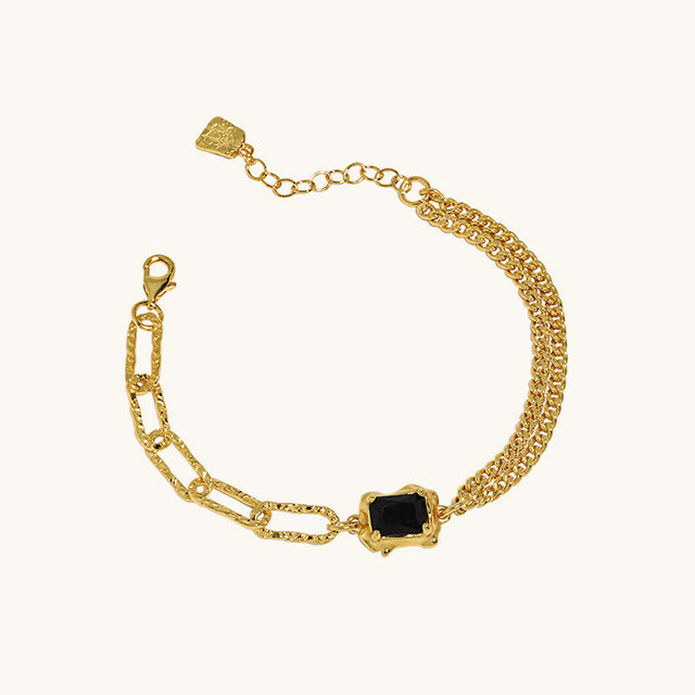 A gold wrist bracelet with black stone.