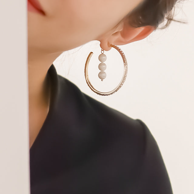 Women wear large gold hoop earrings.