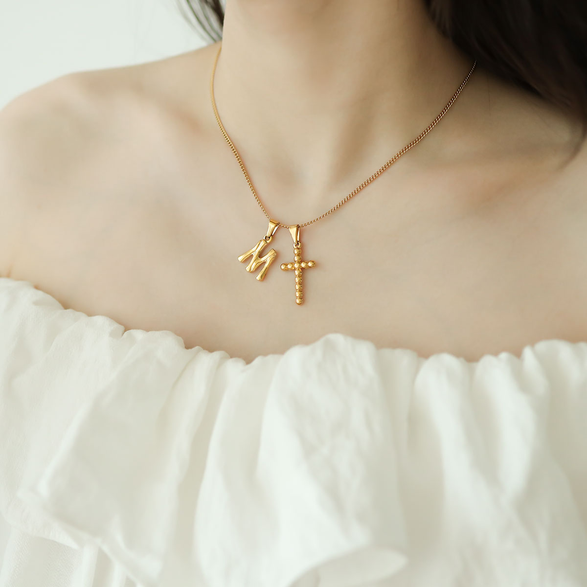 Women wear letter m necklace with cross.