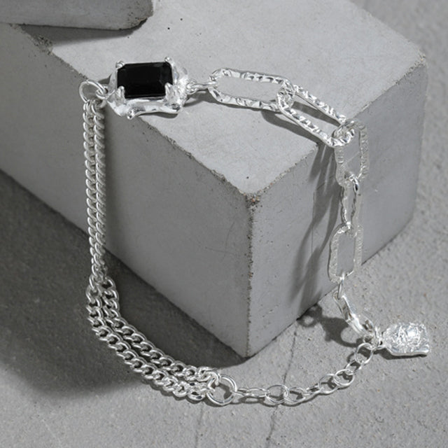 Black stone mens chain bracelets on cement brick. 