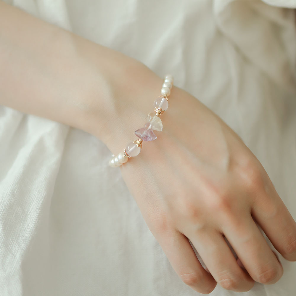 Women wear pearl bracelet with bow.