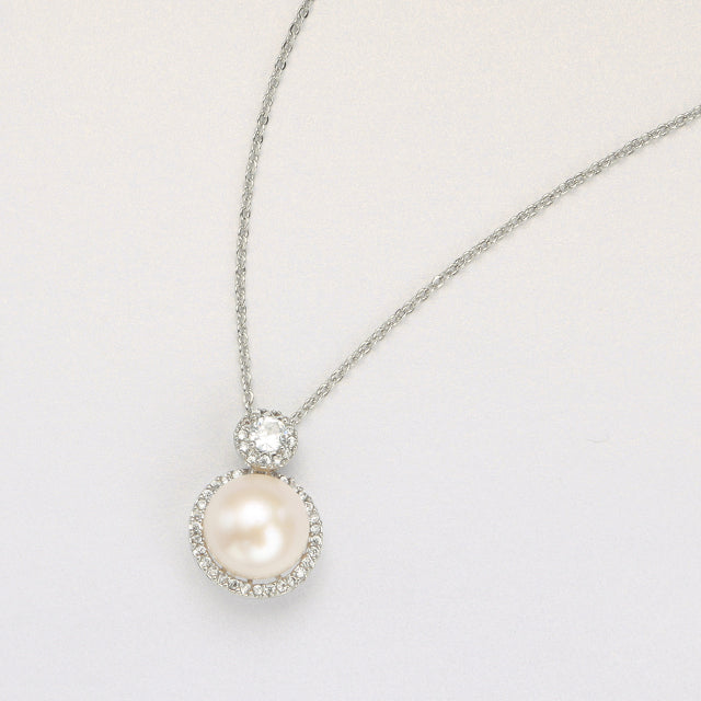 A pearl drop necklace on beige paper.