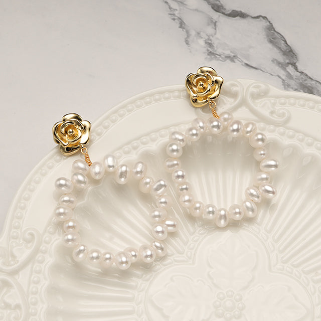A pair of pearl hoop earrings on white plate.