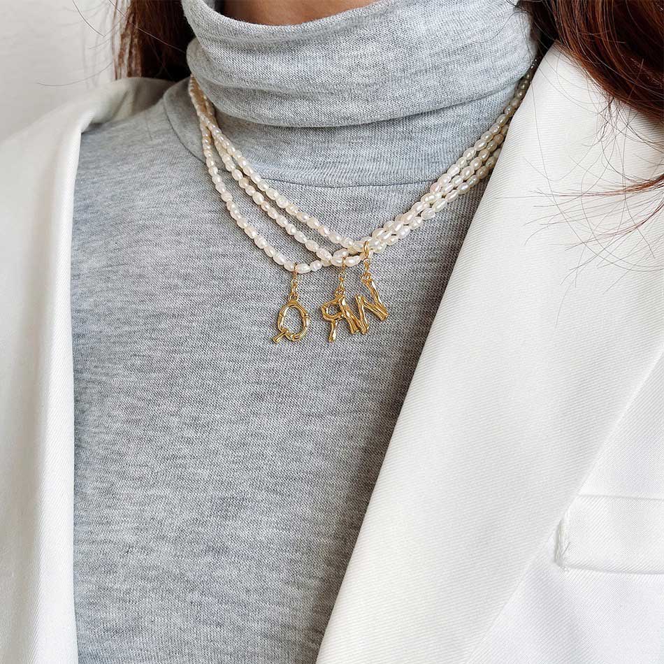 Women wear pearl letter charm necklace.