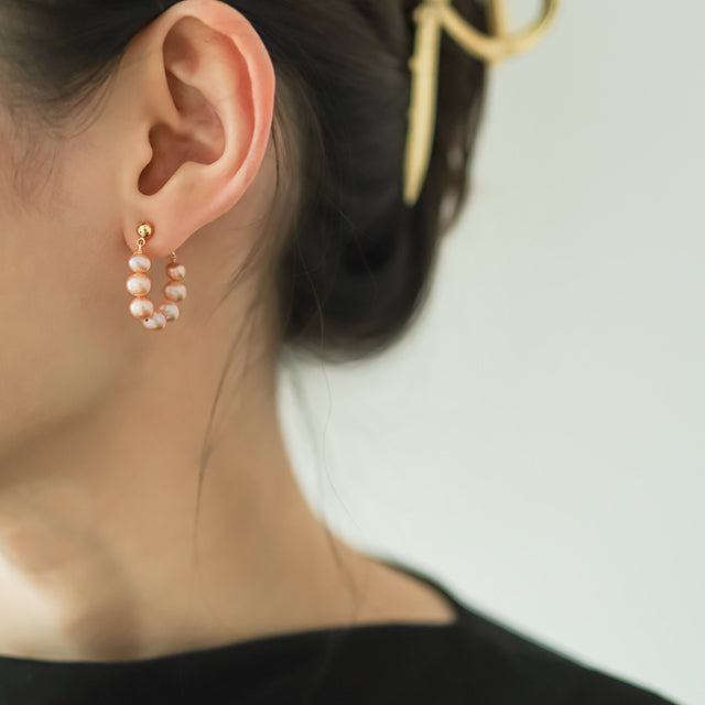 Pink pearl summer earrings on women ear.