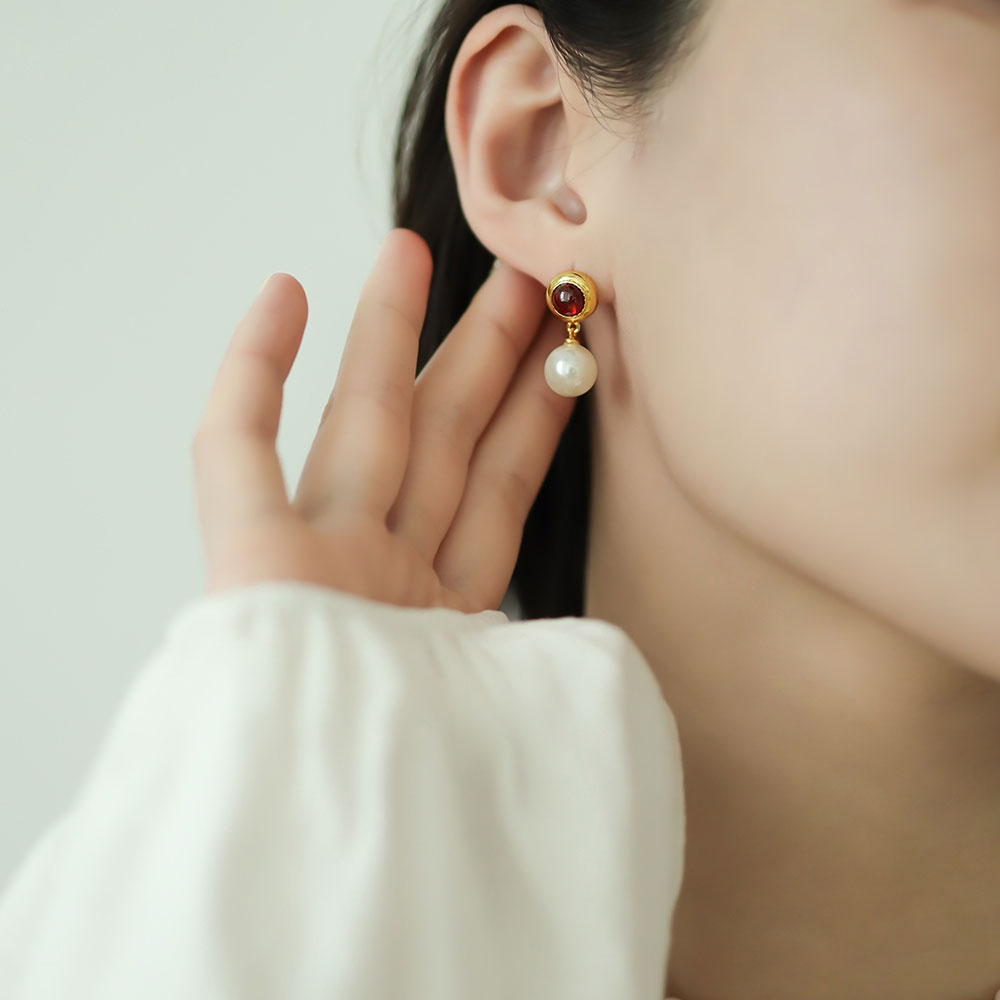 Women in white wear red drop earrings.