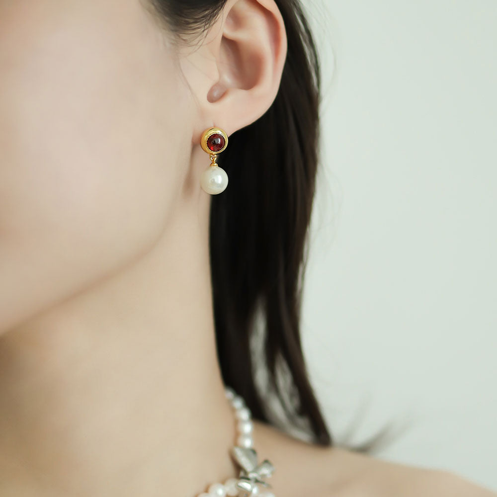 Women wear a red statement earrings with pearl.