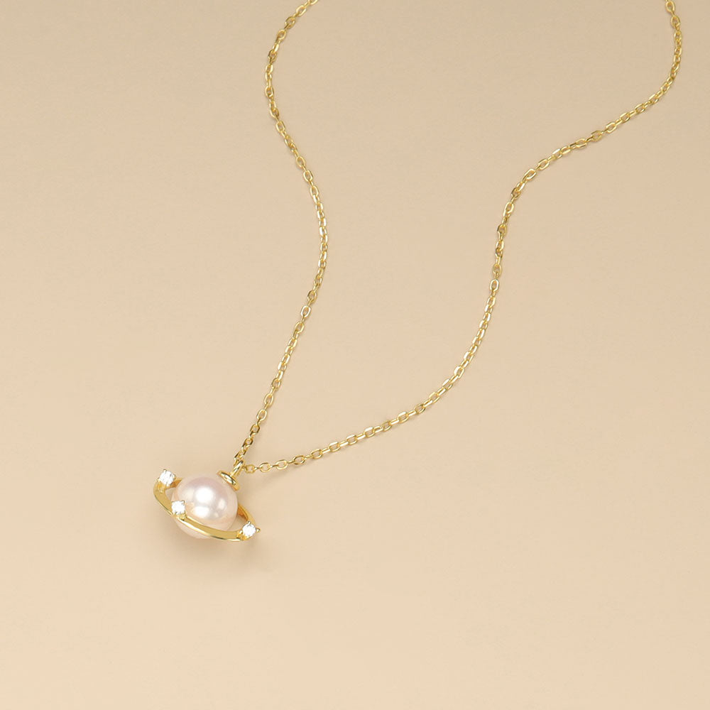 A gold saturn necklace with pearl.