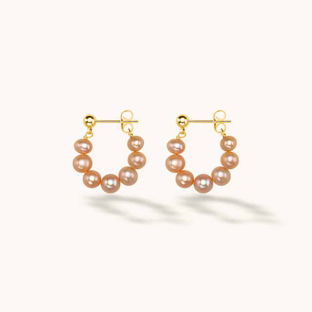 A pair of seven pink pearl hoop earrings.