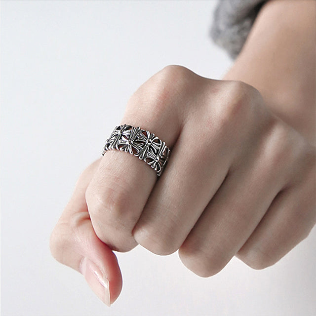Silver cross band ring on finger.