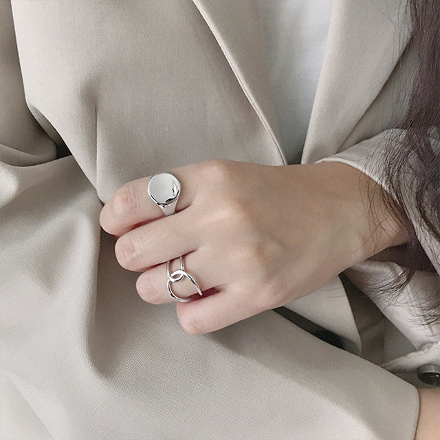 A women in grey suit with two silver designer rings.