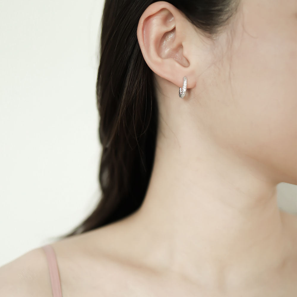 Women wear a silver huggie earring.