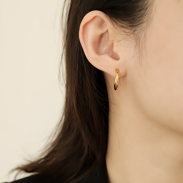 Women wear a simple gold earring.