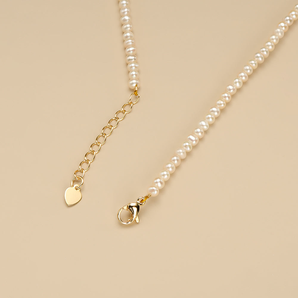 The gold lobster claw clasp on small pearl necklace.