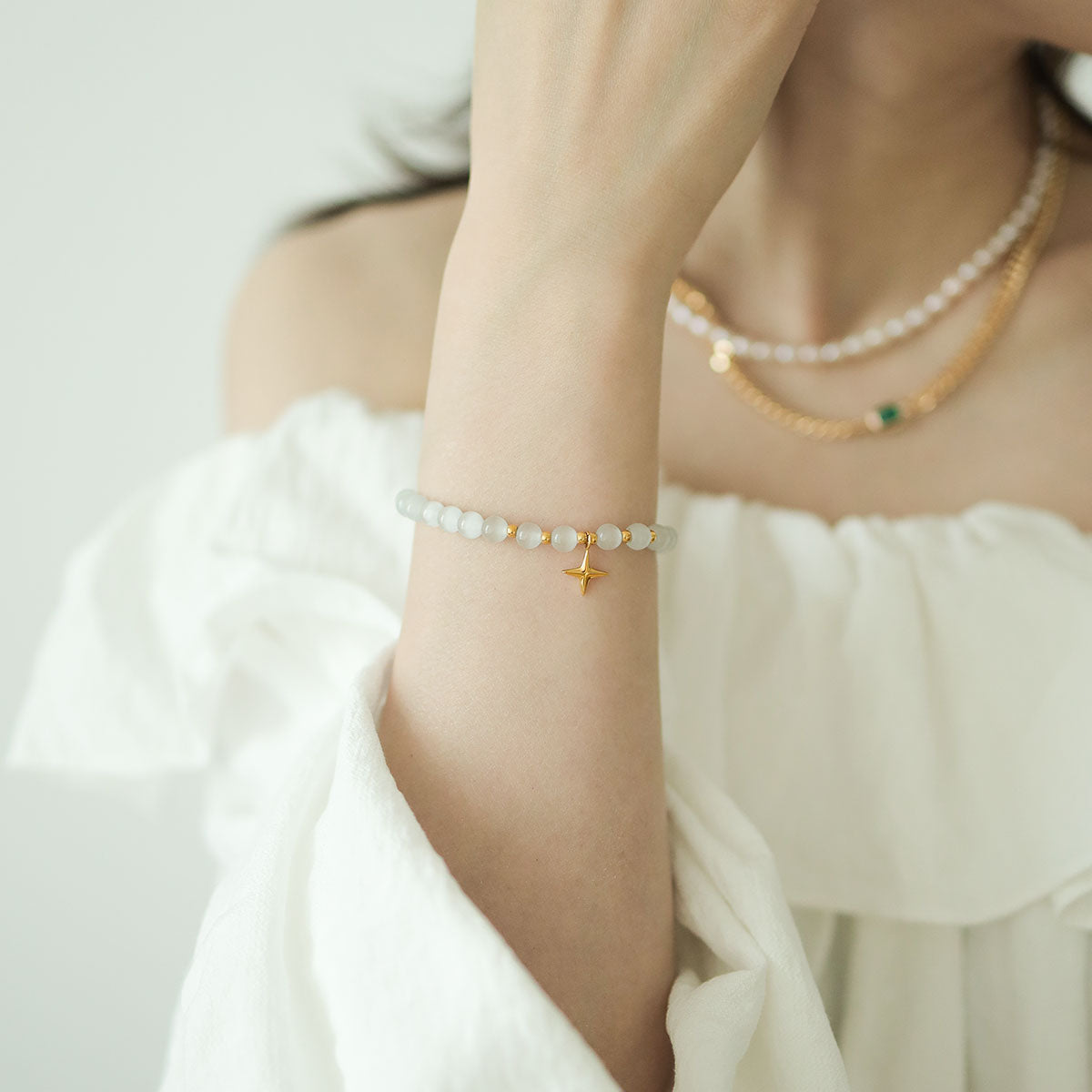 Women wear a star bracelet and pearl necklace.