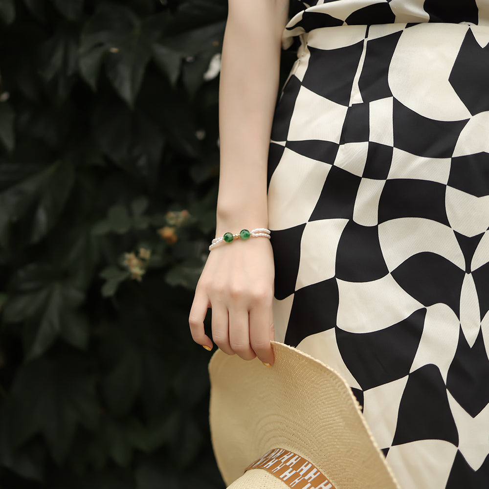 Women hold a straw hat wear a summer pearl bracelet.